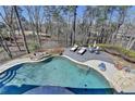Gorgeous backyard pool surrounded by lush greenery and a sun deck with lounge chairs at 6950 Kettering Ln, Suwanee, GA 30024