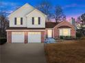 Charming two-story home at dusk with a brick and vinyl exterior and manicured lawn at 6920 Greenfield Ln, Cumming, GA 30028