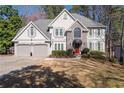Charming two-story home features a manicured lawn, gray siding, stone accents, and a two-car garage at 3202 Eagle Watch Dr, Woodstock, GA 30189