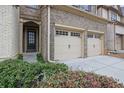 Close up of a two-car garage in a townhome with a brick facade and adjacent front door at 1632 Caswell Pkwy # 8, Marietta, GA 30060