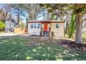 Charming home featuring a bright orange front door, complemented by a well-maintained lawn and surrounding trees at 1256 Elizabeth Sw Ave, Atlanta, GA 30310