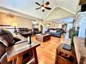 Well-lit living room with hardwood floors, leather seating, and an open layout to the dining area at 2515 Little John Ct, Cumming, GA 30040