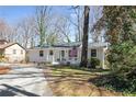 Inviting single-story home with front porch, American flag, and driveway through a wooded landscape at 3841 Admiral Dr, Atlanta, GA 30341