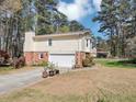 Side view of house with vinyl siding, brick, a large garage door, and landscaping; view of surrounding neighborhood at 5221 La Paloma Sw Dr, Lilburn, GA 30047