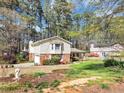A home with vinyl siding, brick accents, lush trees, and a garden with green grass and decorative statue at 5221 La Paloma Sw Dr, Lilburn, GA 30047