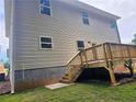 Exterior side view of the home, showing a wooden deck overlooking the green backyard at 309 Melanie Ct, Bowdon, GA 30108