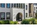 Close up of the home's arched entryway, white brick, manicured landscaping, and dark trim at 6616 Aria Village Dr, Atlanta, GA 30328