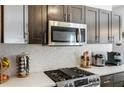 Close-up of a kitchen with stainless steel microwave, gas range, and white backsplash at 949 Tumlin Trce, Lawrenceville, GA 30045