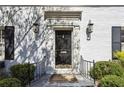 Elegant front door with black hardware, flanked by sconces and lush greenery at 435 Collier Nw Rd, Atlanta, GA 30309