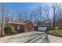 Red brick home with attached garage and a long driveway, surrounded by mature trees at 5060 Governors Walk Dr, Canton, GA 30115