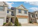 Charming two-story townhome featuring a stone facade and attached garage with manicured landscaping at 5890 Vinyard Ln, Cumming, GA 30041