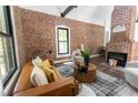 Modern living room with exposed brick wall, fireplace, hardwood floors, and comfortable seating arrangement at 6592 Factory Shoals Sw Rd, Mableton, GA 30126