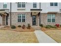 Close-up of a townhouse entrance featuring brick steps, dark door, and manicured landscaping at 1273 Harvest Park Ln, Suwanee, GA 30024