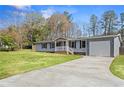 Inviting one-story home with a driveway and attached garage, surrounded by lush greenery and mature trees at 1833 Lost Mountain Rd, Powder Springs, GA 30127
