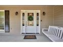 Inviting front porch with a swing, decorative door, and stylish sconces at 3075 Wood Valley Dr, Mcdonough, GA 30253