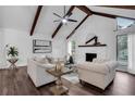 Bright open-concept living room with vaulted ceilings with beams, modern furniture, hardwood floors, and fireplace at 2512 Hidden Hills Dr, Marietta, GA 30066