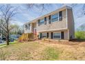 Charming two-story home with tan siding, black shutters, a red front door, and a wooden porch and rails at 5415 Tracey Dr, Stone Mountain, GA 30088