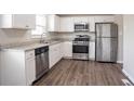 Updated kitchen featuring stainless steel appliances, white cabinetry, granite countertops, and wood-look flooring at 5415 Tracey Dr, Stone Mountain, GA 30088