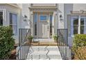 Elegant front door with decorative molding, sidelights, and black iron railing, complemented by manicured landscaping at 2890 Olde Town Park Dr, Norcross, GA 30071