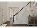 Elegant staircase with dark wood floors and a white banister leading to a dining room with lots of natural light at 2890 Olde Town Park Dr, Norcross, GA 30071