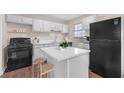 Modern kitchen featuring white cabinetry, a central island, and sleek black appliances, offering a stylish design at 4690 Big Valley Ct, Stone Mountain, GA 30083