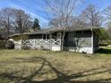 A side view of the house with green siding, white lattice porch, and overgrown lawn at 406 Dallas Hwy, Villa Rica, GA 30180