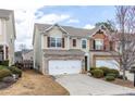 View of the inviting two-story townhome featuring a two-car garage and mature trees at 1212 Lake Point Way, Suwanee, GA 30024