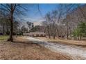 Peaceful view of a single-story home featuring a driveway and set in a wooded location at 537 Pine Shadows Dr, Dallas, GA 30157