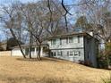 Split-level home with gray brick and vinyl siding and windows with black shutters at 1888 Peeler Rd, Dunwoody, GA 30338