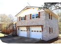 Charming home features a brick facade, white trim, a dark roof, and an attached two-car garage at 2110 E Cherokee Dr, Woodstock, GA 30188