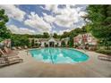 Community pool area featuring lounge chairs, lush trees and well maintained building exterior at 420 Heritage Park Nw Trce # 22, Kennesaw, GA 30144