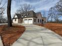 A newly constructed home with a two-car garage and a long concrete driveway surrounded by a large yard at 6110 Harvest Way, Cumming, GA 30028