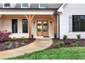 Elegant front entrance with double glass doors, wood beams, and manicured landscaping at 6110 Harvest Way, Cumming, GA 30028