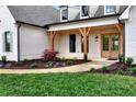 Inviting covered porch featuring natural wood supports and a beautifully landscaped garden at 6110 Harvest Way, Cumming, GA 30028