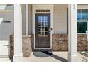 Close-up of the front door with brick accents, a covered porch, and stylish columns at 311 Ivy Chase Loop, Dallas, GA 30157