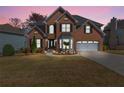 Charming brick home with manicured lawn, two-car garage, and an illuminated front entrance at dusk at 1264 Ridge Vista Nw Ct, Lawrenceville, GA 30043