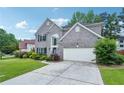 Attractive two-story home with a brick facade, a well-kept lawn, and a paved driveway leading to the garage at 2848 Stockbridge Way, Dacula, GA 30019