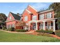 Stunning two-story red brick home featuring a welcoming front porch and lush landscaping at 5114 Parkwood Oaks Ln, Mableton, GA 30126