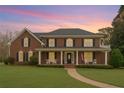 Charming two-story brick home featuring a covered front porch, columns, and a well-maintained lawn at 210 Little River Farms Trl, Canton, GA 30115