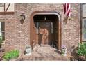 Elegant brick entryway features a classic arched doorway, sconce lighting, and potted flowers at 2702 Long Lake Ne Ter, Roswell, GA 30075