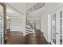 Bright foyer featuring dark hardwood floors, staircase with white railings, and transom-window doors at 6040 Ashborough Park, Cumming, GA 30040