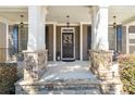 Inviting front porch with stone pillars, neutral colors, elegant light fixtures and a welcoming front door at 4183 Hill House Sw Rd, Smyrna, GA 30082