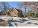 Side exterior view of a two-story brick home surrounded by lush greenery at 7740 Sagebrush Dr, Atlanta, GA 30350