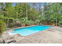 Backyard swimming pool surrounded by a concrete deck, mature trees and lush landscaping at 7740 Sagebrush Dr, Atlanta, GA 30350