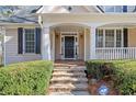 Inviting front porch with stone steps, black door, white columns, and neat landscaping at 345 Crown Vetch Ln, Alpharetta, GA 30005