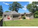 View of the home's exterior featuring an enclosed porch, lawn, and mature trees on a sunny day at 584 Cherokee Ne St, Marietta, GA 30060