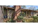 Rear exterior with brick chimney, covered porch, mature foliage, and seating at 4858 Westridge Dr, Norcross, GA 30093