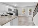 Bright kitchen features white cabinets, stainless steel appliances, and wood flooring at 3575 Bonneville Dr, Cumming, GA 30041