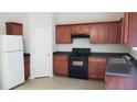 Well-lit kitchen features wooden cabinets, dark countertops, white refrigerator, and black appliances at 2102 Executive Dr, Duluth, GA 30096