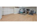Spacious basement with exercise equipment, light laminate flooring, and white storage cabinets at 7085 Wakehurst Pl, Cumming, GA 30040
